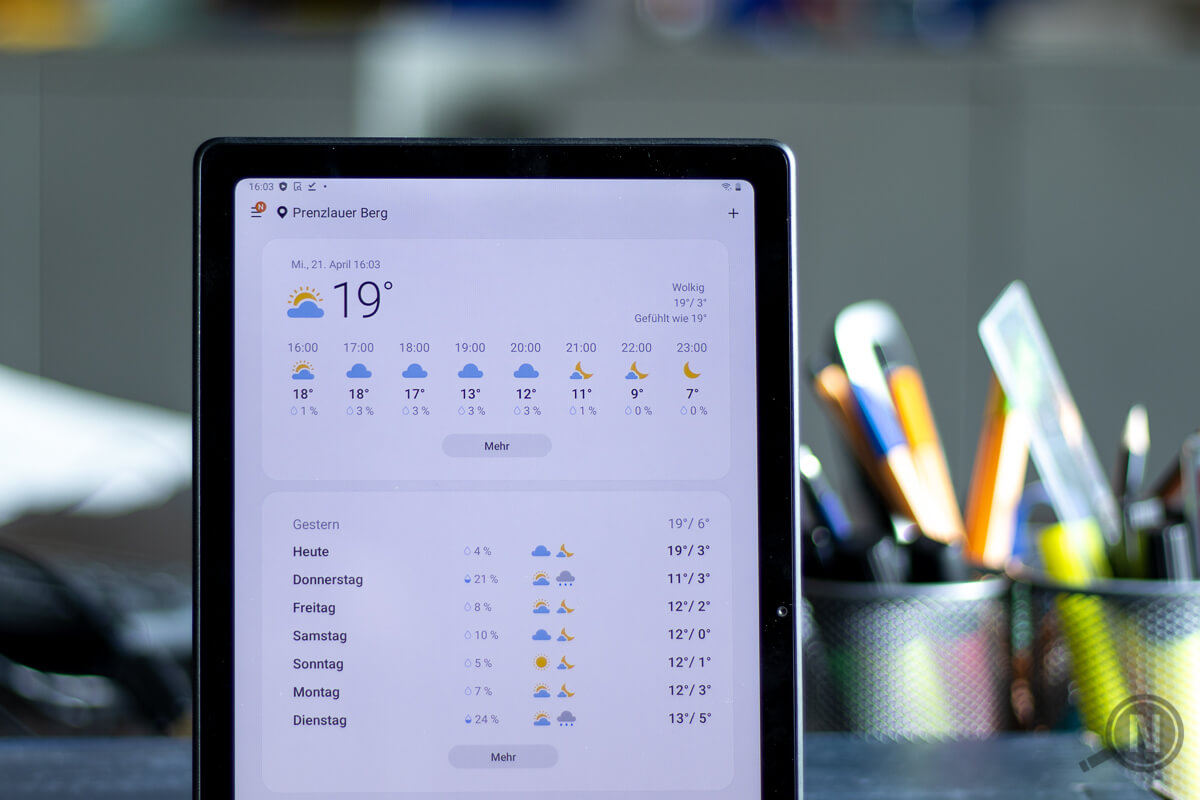Ein senkrecht aufgestelltes Android-Tablet zeigt das Wetter der kommenden Tage an. Unscharfer Hintergrund mti Büroeinrichtung.