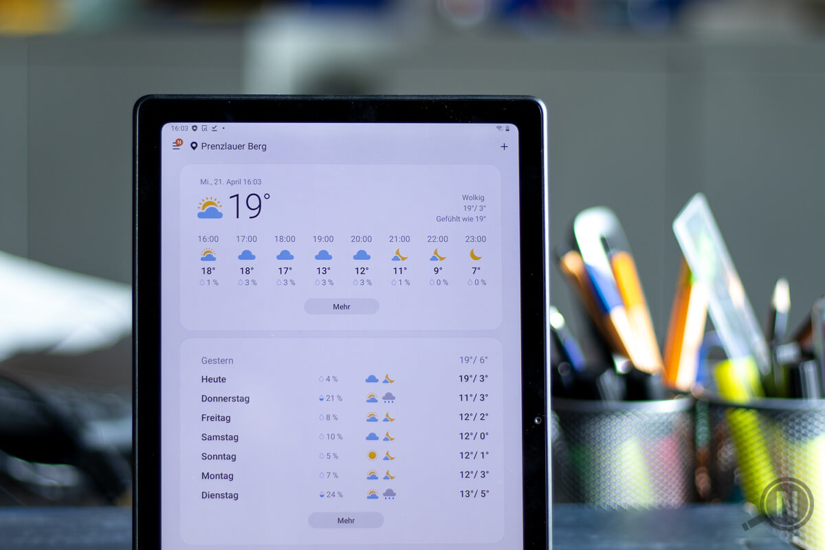 Ein senkrecht aufgestelltes Android-Tablet zeigt das Wetter der kommenden Tage an. Unscharfer Hintergrund mti Büroeinrichtung.