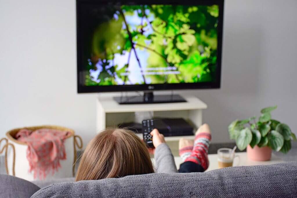 Frau auf Sofa guckt Fernseh