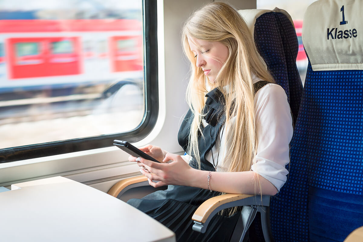 Maedchen sitzt im Zug mit Tablet