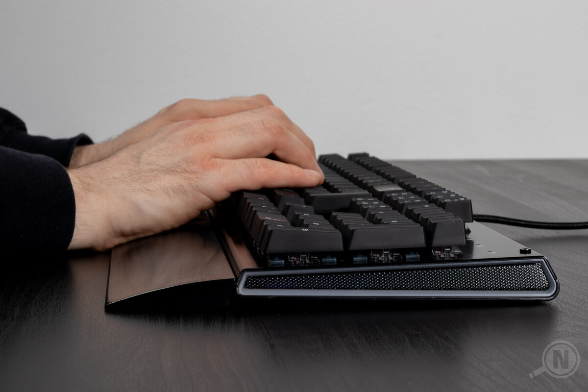 Gaming-Tastatur mit Handballenauflage und tippenden Haenden.