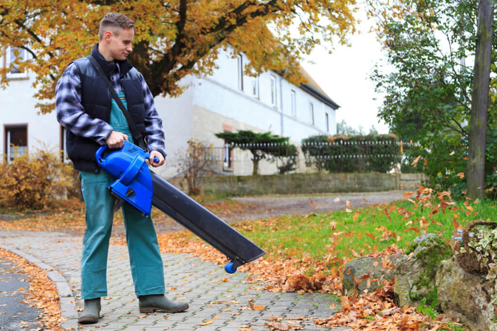 Mann bläst Gehweg frei