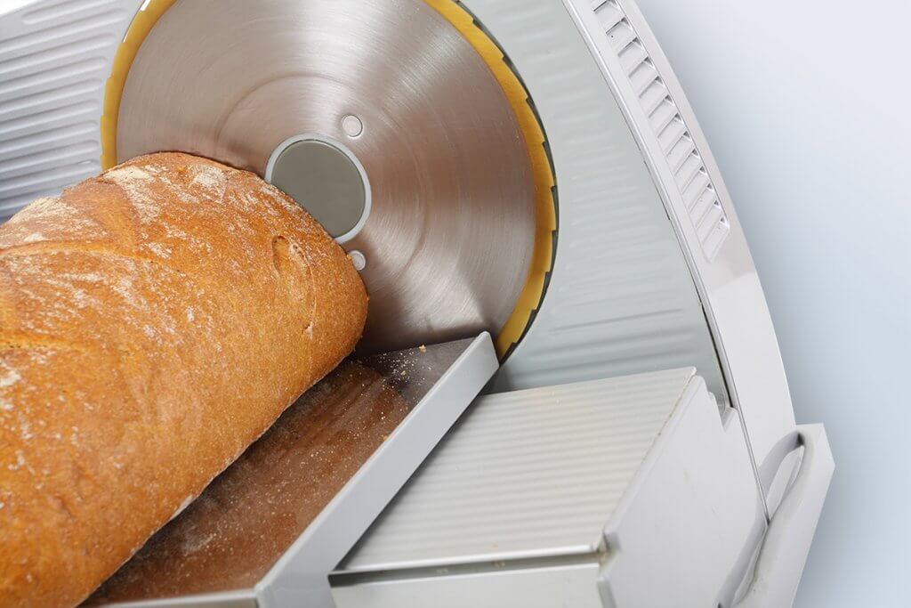 frisches Brot wird mit Allesschneider geschnitten