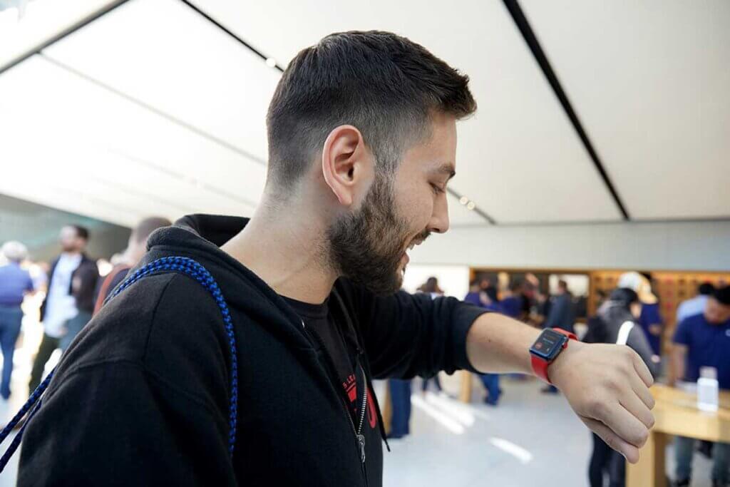 junger Mann schaut auf Apple Watch