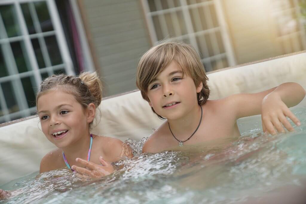 zwei kinder sitzen im aufblasbaren whirlpool