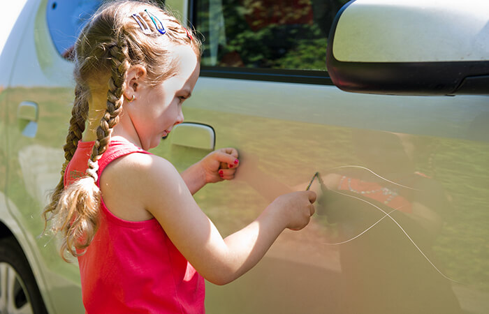 Kind zerkratzt den Lack einer Autotür