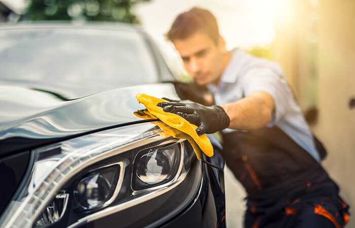 Person poliert ein Auto mit Tuch