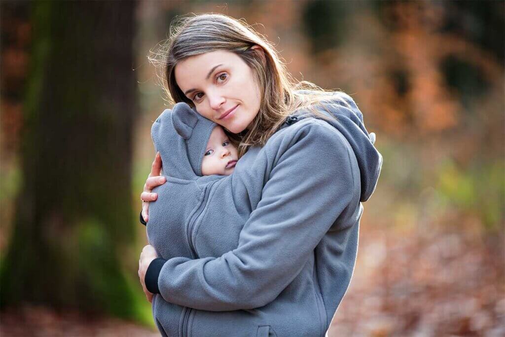 Mama trägt ihr Baby in Pullover Babytrage