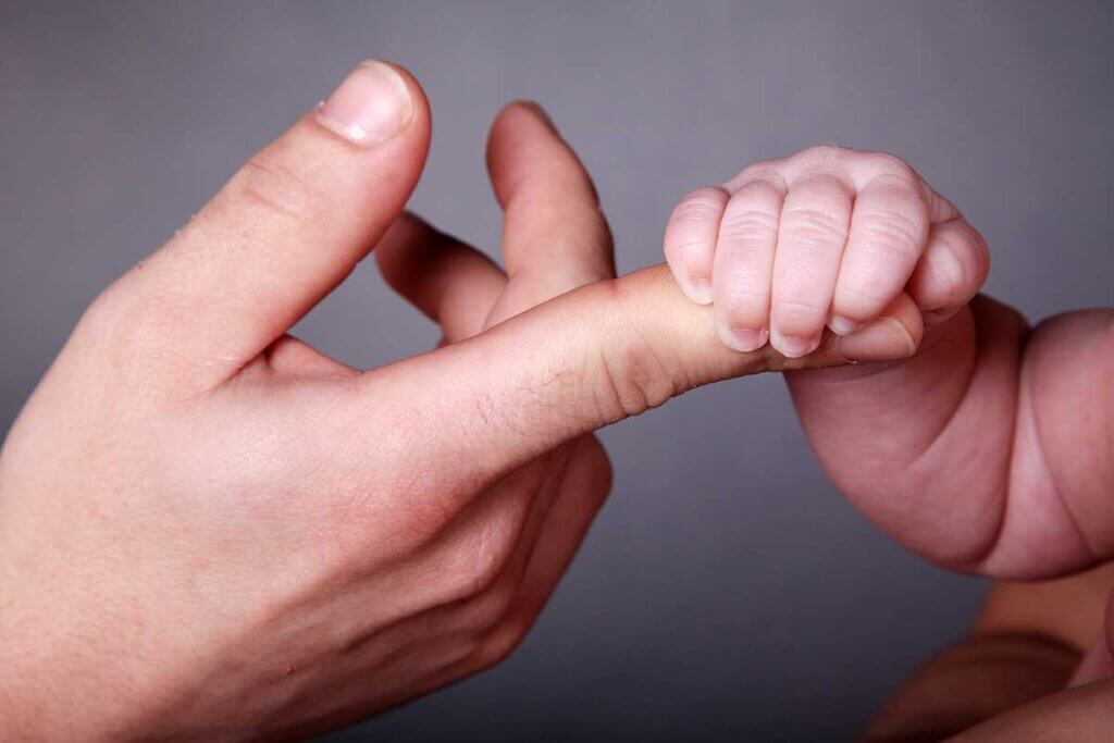 Säugling greift nach einem Finger