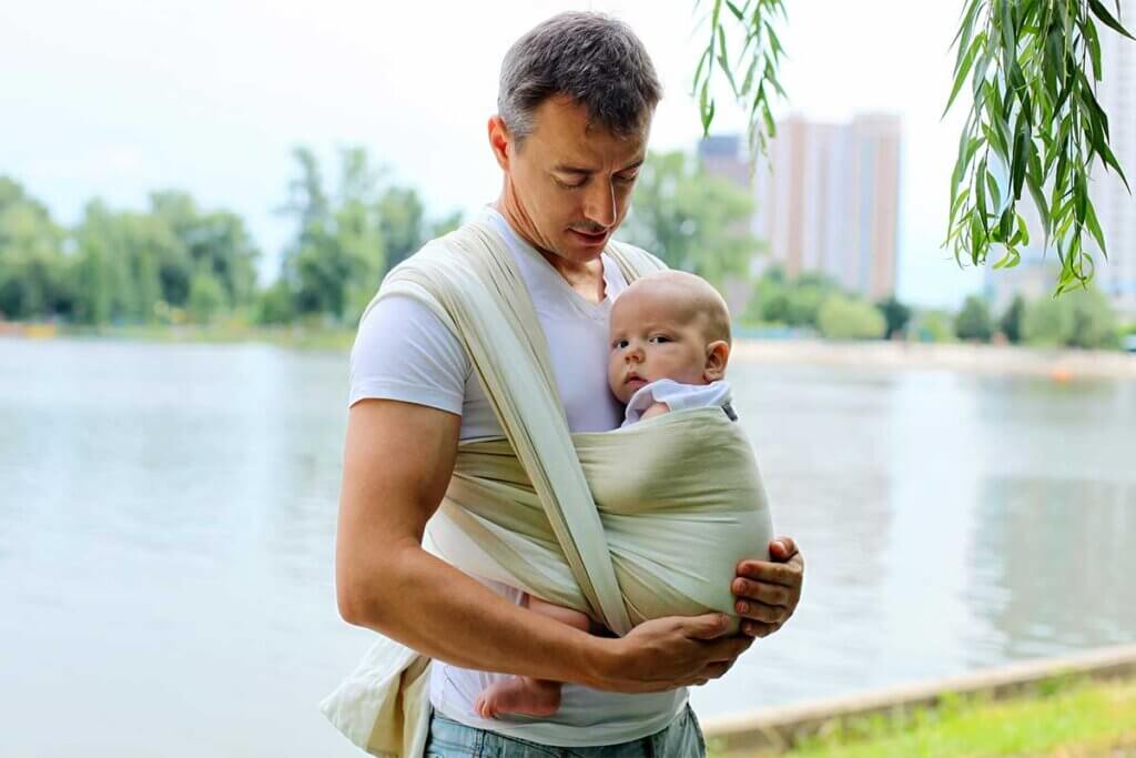 Vater trägt Baby in Tragetuch
