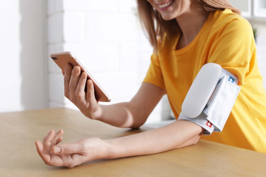 Frau checkt Blutdruck über Verbindung mit Smartphone