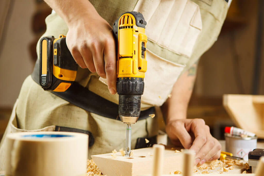 Handwerker bohrt ein Loch in Holzbalken