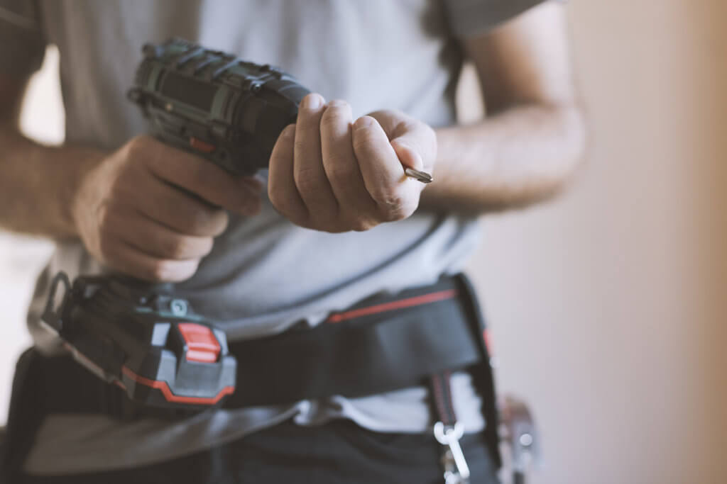 Handwerker schraubt an Bohrmaschine