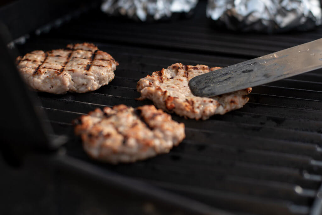 Burgerpatties liegen auf einem Grillrost