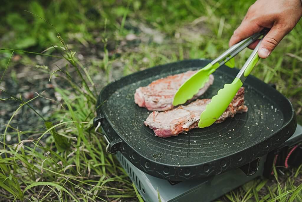 Zwei Steaks werden auf einem kleinen Gasgrill gebraten