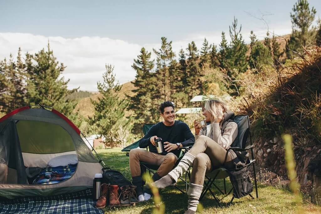 Paar sitzt in Campingstuehlen in der Natur. 