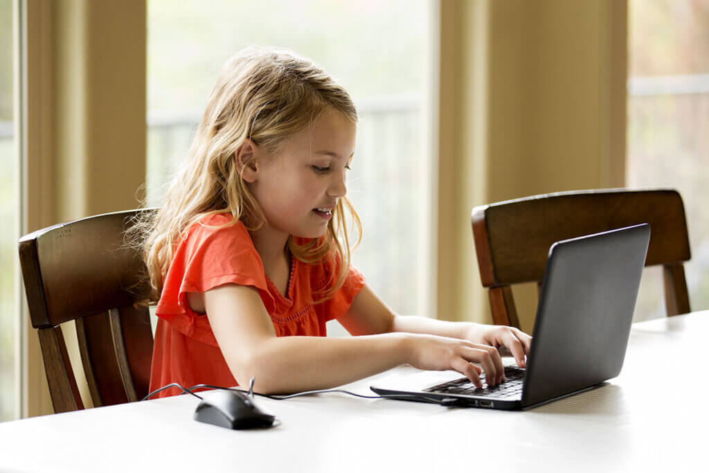 junges Mädchen sitzt zu Hause an Laptop