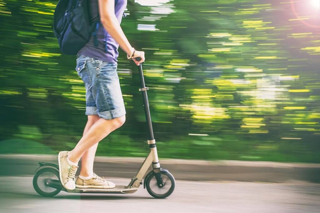 Frau fährt auf Roller durch Park