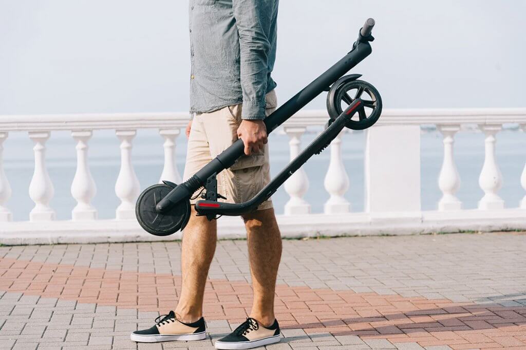Person hält Cityroller in der Hand