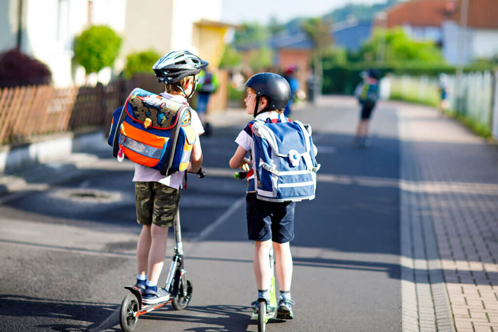 zwei Schuljungen sind auf Cityrollern unterwegs