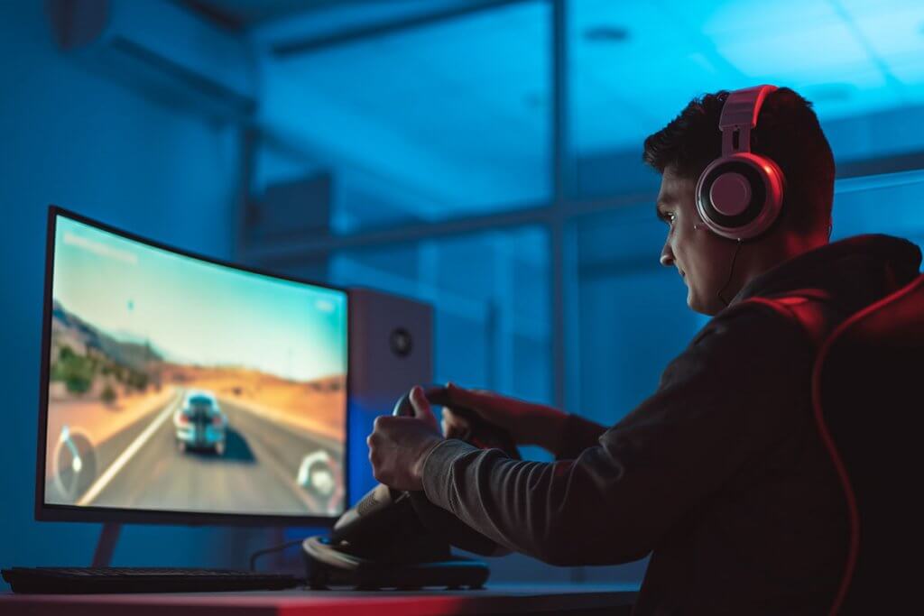 Man spielt Rennspiel an Curved-Monitor
