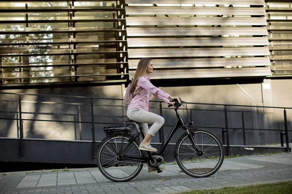 junge Dame fährt E-Bike durch Stadt