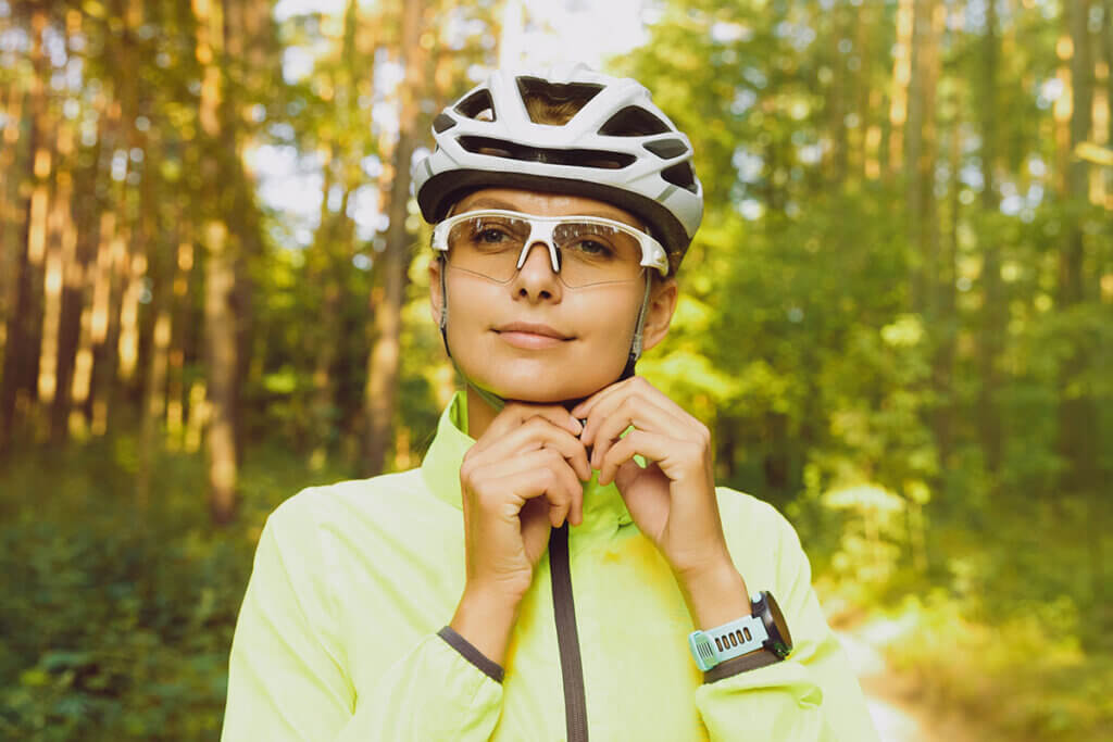 frau schliesst kinnriemen am fahrradhelm