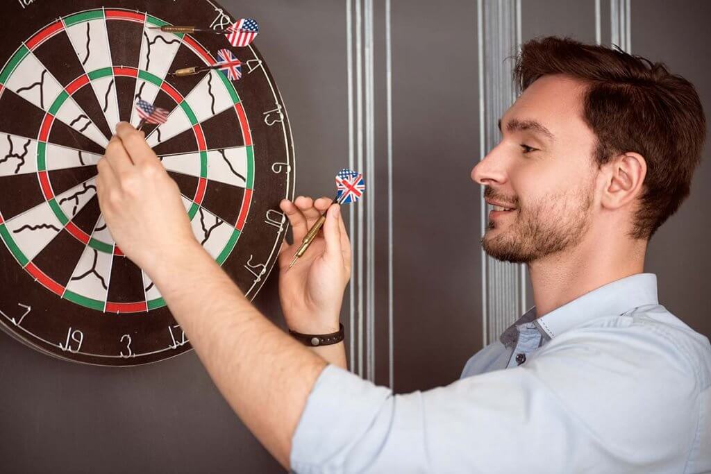 Mann zieht Pfeile aus Dartscheibe