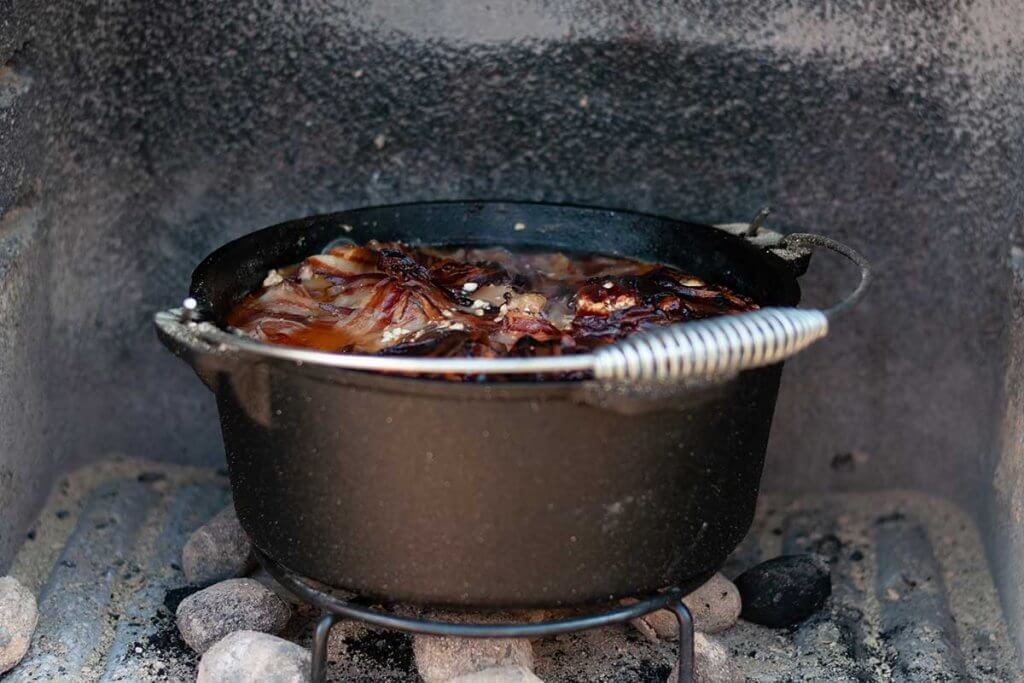 offener Dutch Oven mit Essen auf Feuerstelle