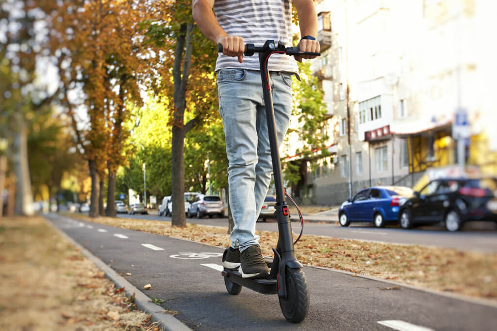 Mann auf Elektro-Scooter faehrt durch Stadt