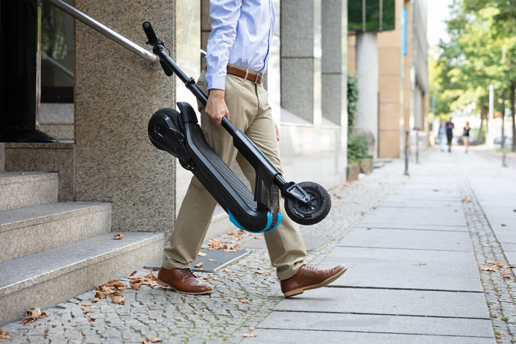 Mann verlaesst Arbeit und traegt Scooter
