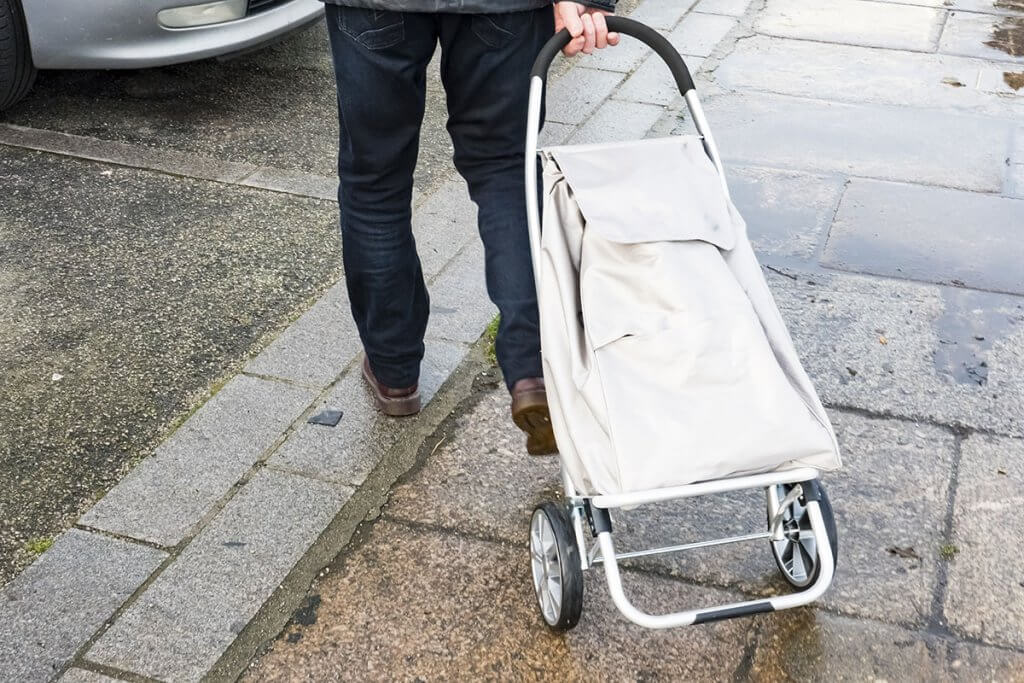 Mann zieht Einkaufstrolley hinter sich her