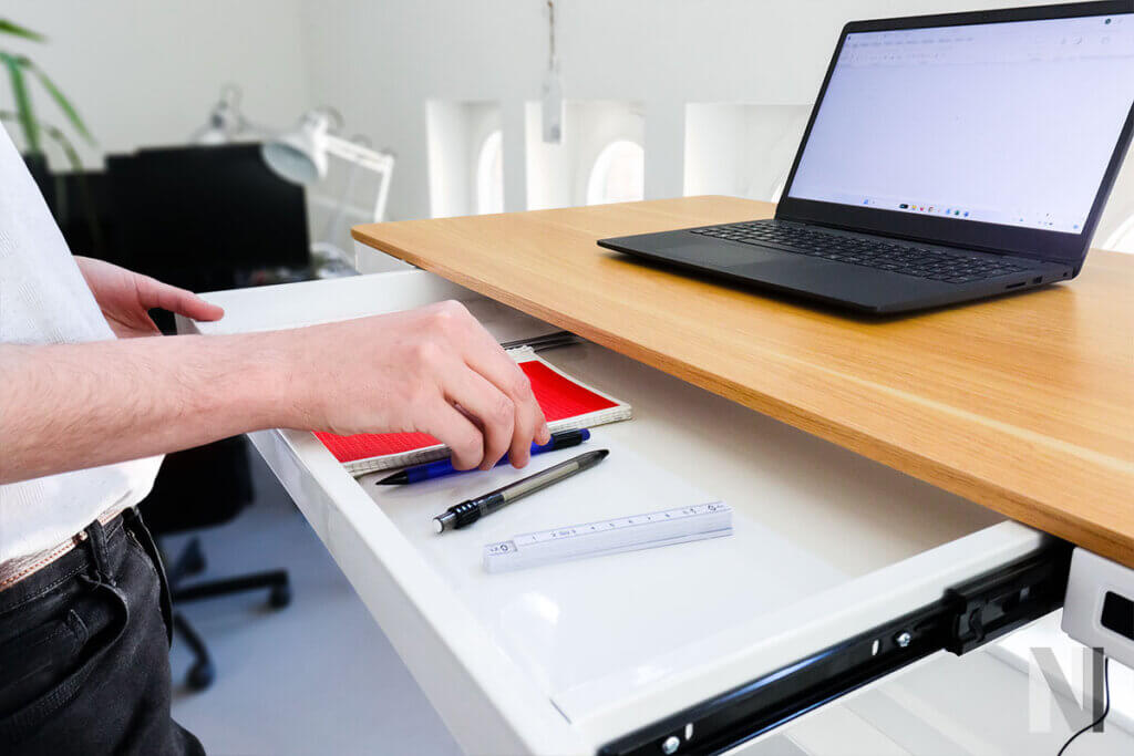 person legt stift zu block und utensilien in die schublade des comhar