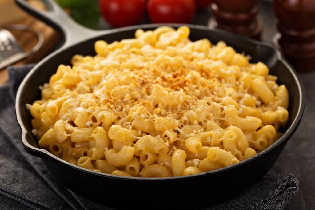 Maccaroni mit Kaese in einer Pfanne in Kueche