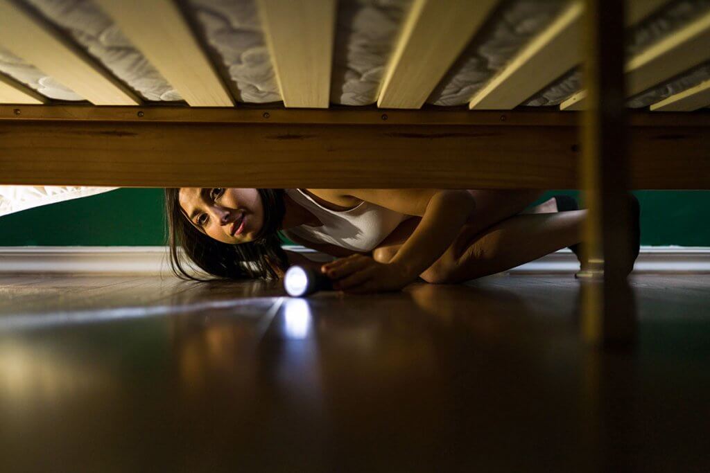Person schaut unter ein Bett