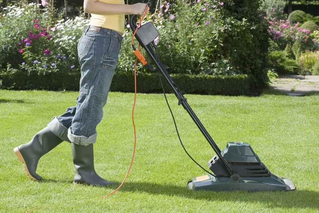 Frau beim Rasenmähen im Garten