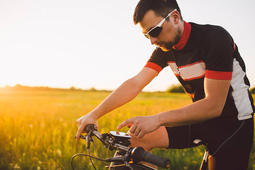 Fahrradfahrer am Feld bedient Fahrrad-Navi