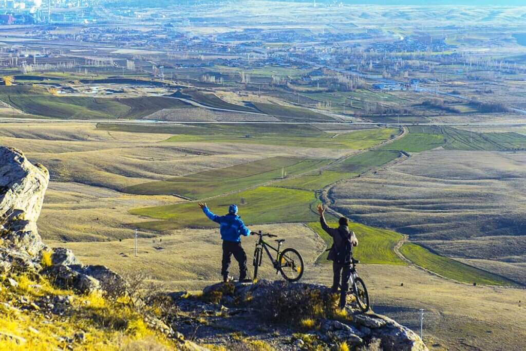 Fahrradfahrer stehen auf Berg und schauen auf Landschaft