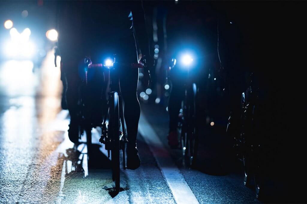 Gruppe von Fahrradfahrern faehrt mit Beleuchtung durch Nacht