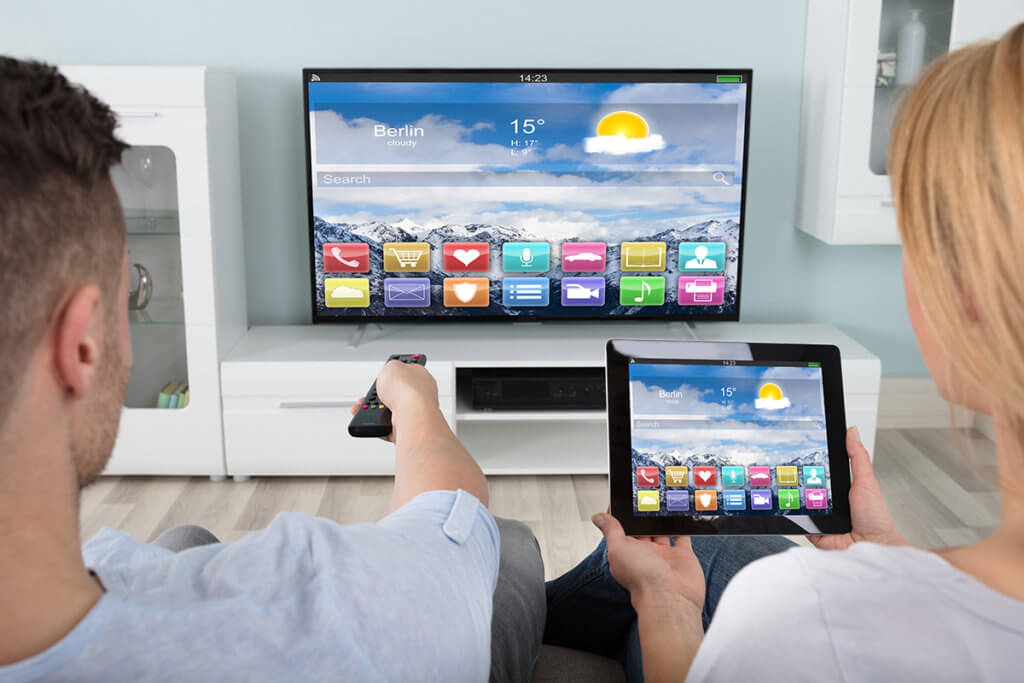 Paar sitzt vor Fernseher - Frau nutzt Tablet