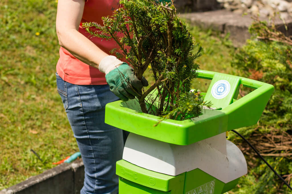 Frau macht Gartenarbeit mit Haecksler
