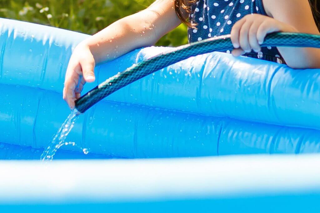 Mädchen füllt Pool mit Wasser