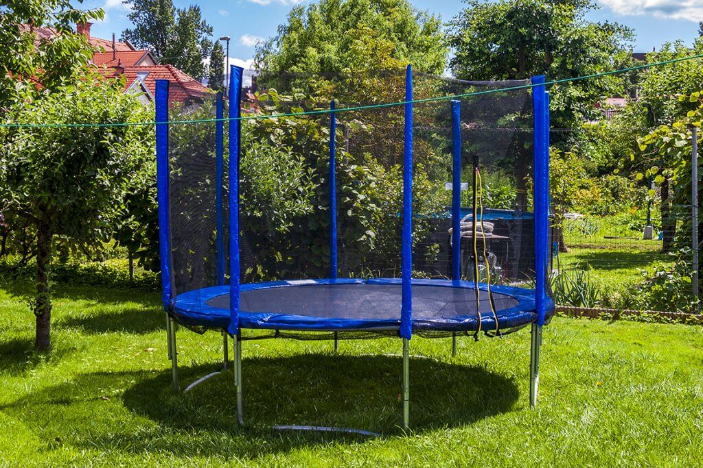 großes, blaues Trampolin steht in Garten