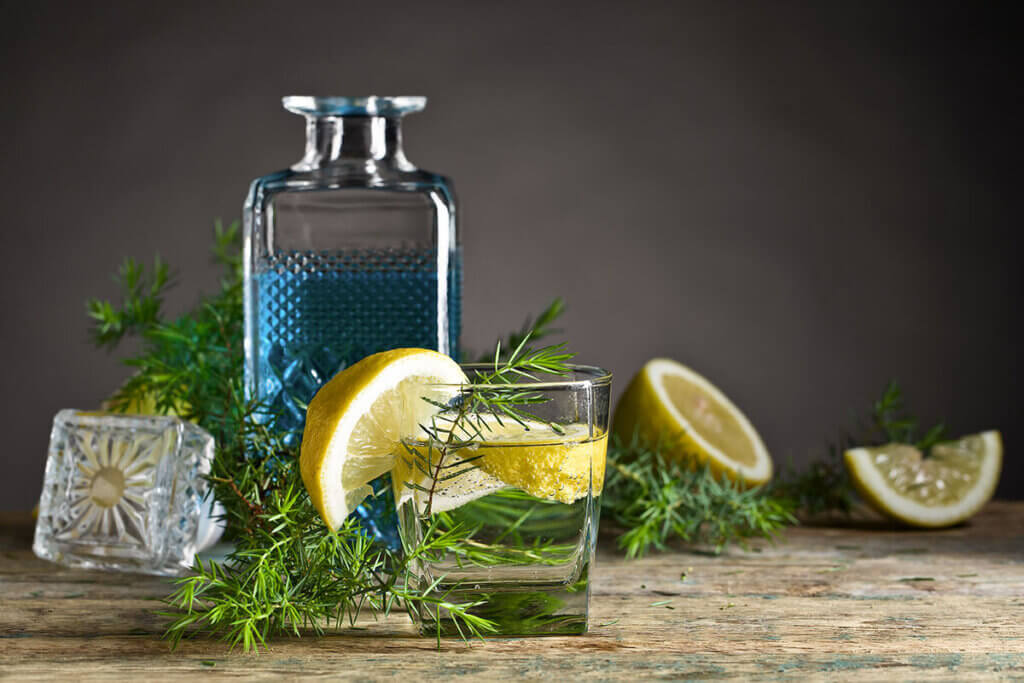 blauer gin mit tonic und zitrone auf holztisch
