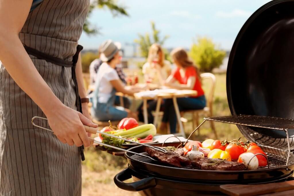 Frau wendet Grillgut mit Grillzange