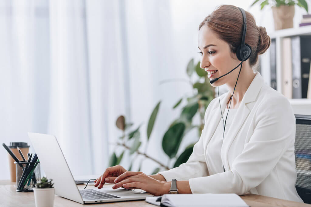 Frau arbeitet mit Headset am Laptop