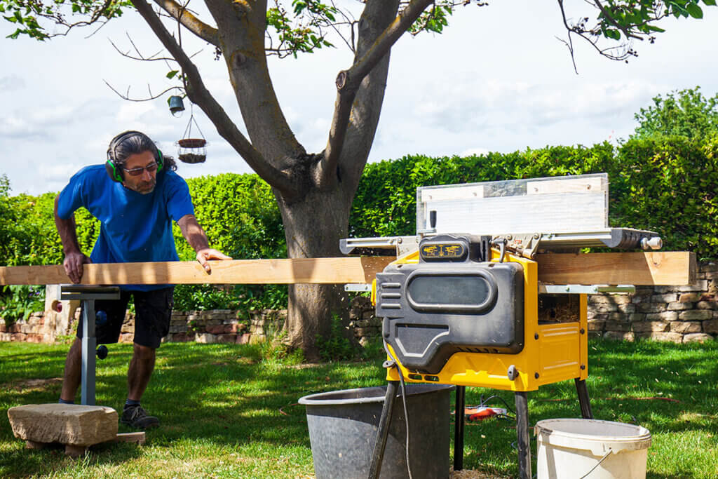 person arbeitet mit hobelmaschine im garten