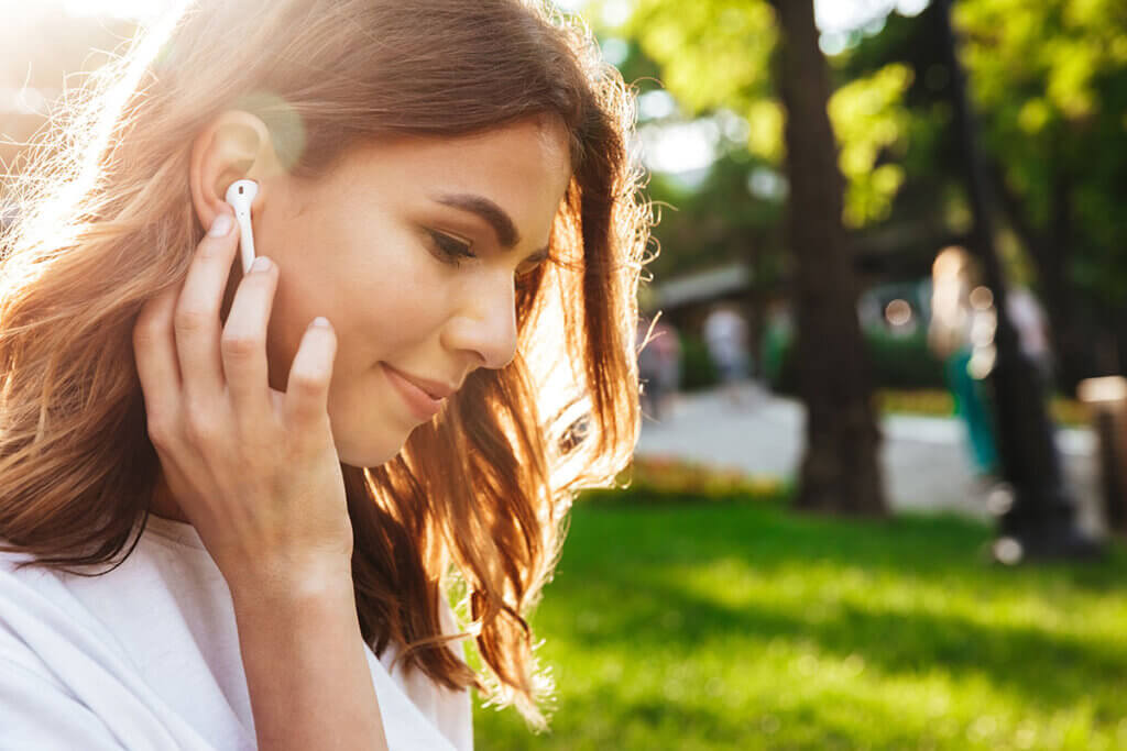 Frau hört Musik im Park mit Kopfhörern
