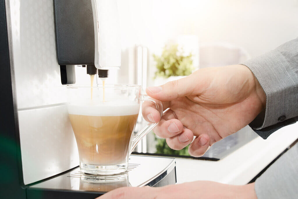 Mann macht sich mit Padmaschine Kaffee