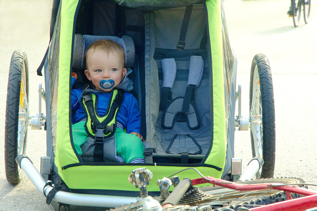 Kleinkind sitz in grünen Fahrradanhänger